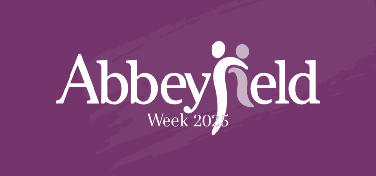 White ‘Abbeyfield Week 2025’ text on a purple background, featuring two abstract human figures forming part of the letter ‘f’ in Abbeyfield, highlighting this special event.