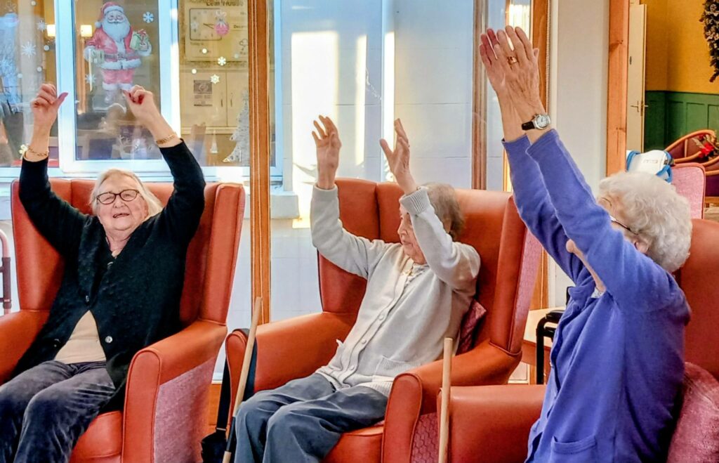 A group of people sitting in chairs with their hands raised, enjoying music and lively activities, creating a vibrant and festive atmosphere at the run.